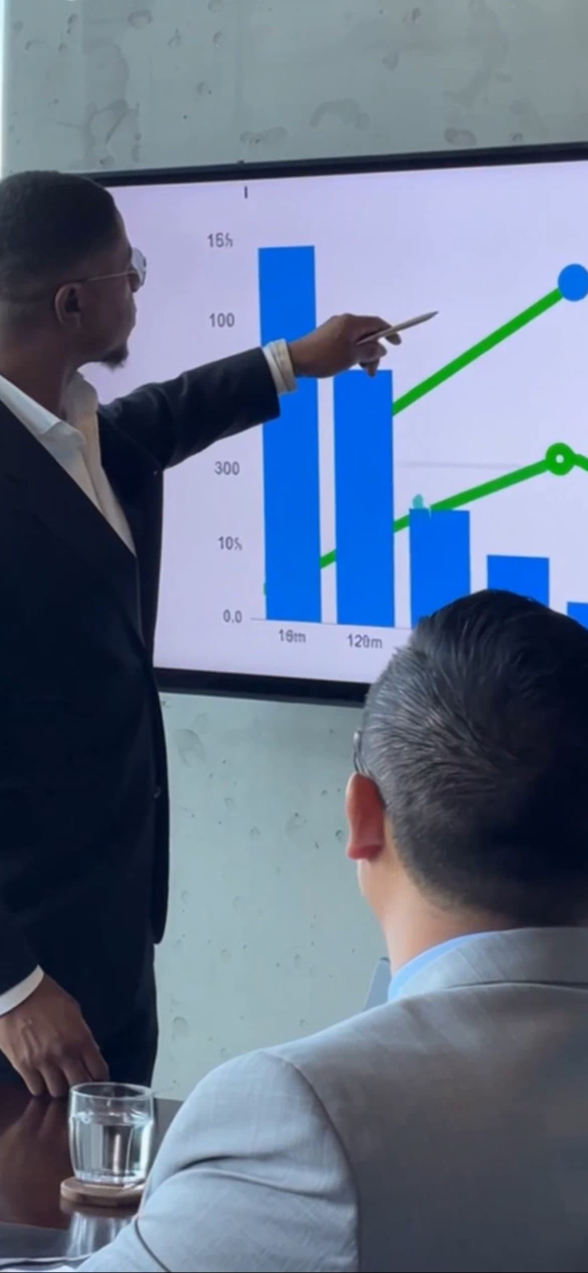 Professional man points at a digital screen showing business growth charts during a meeting.